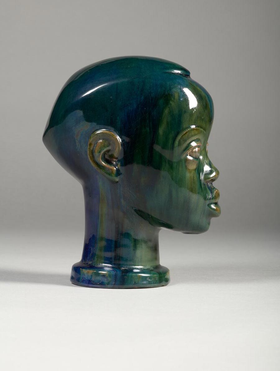 A glazed terracotta head in deep blues and greens facing right.