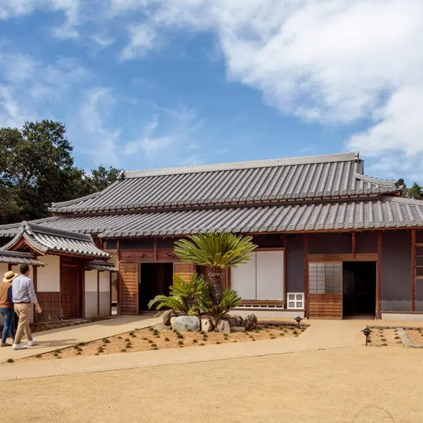 A traditional Japanese home with a gravel courtyard, on a sunny day.