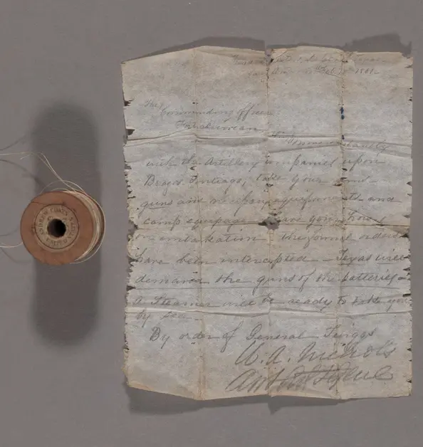 A spool of thread and a written note on folded paper.