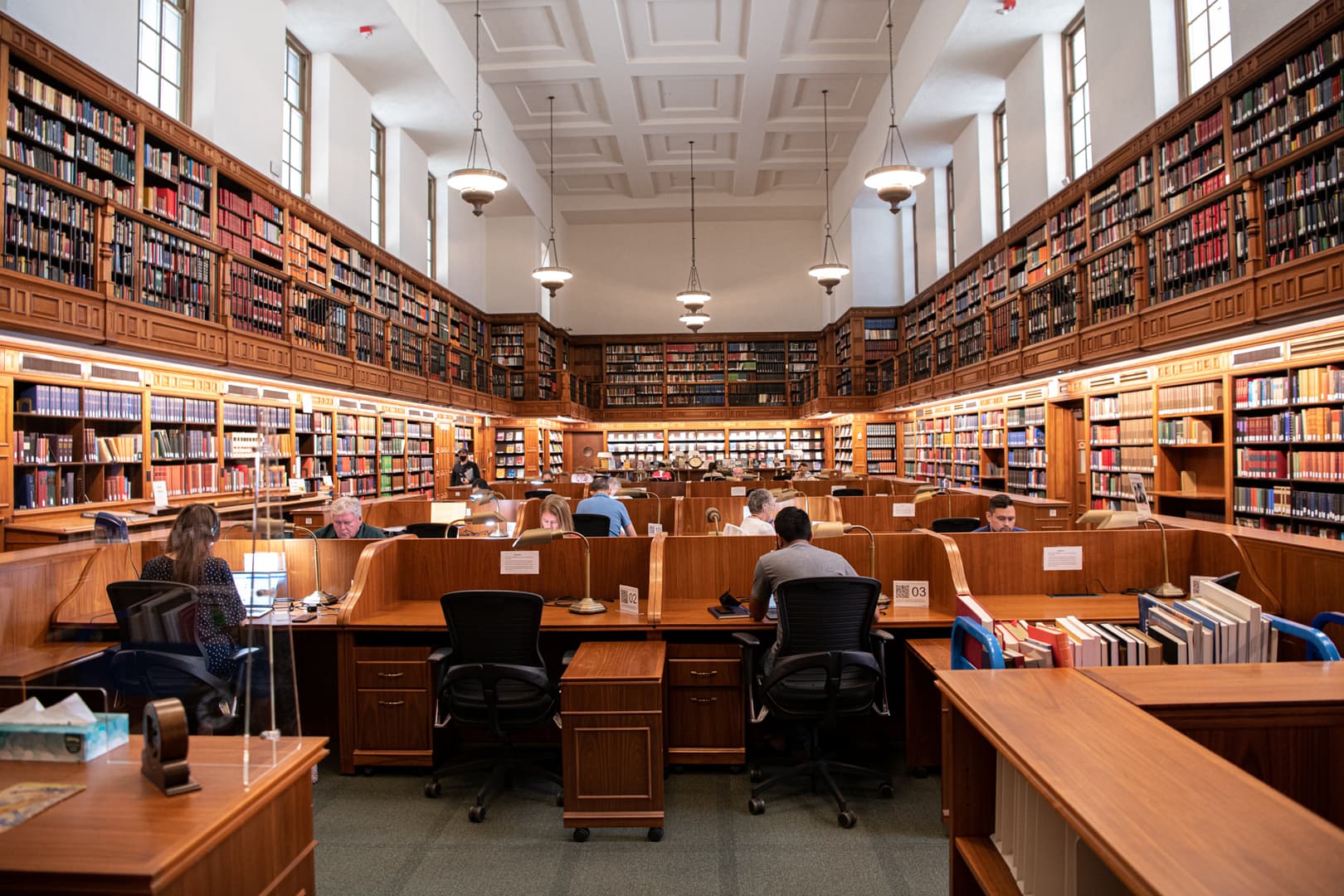 People sit in a library with tables and books.