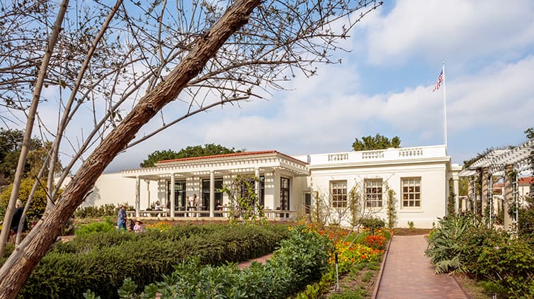 The side exterior of a restored 1910s building stands among a garden.