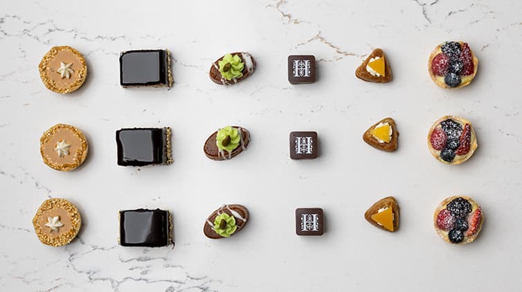 Three rows of small dessert finger foods is set out in a grid pattern on a table.