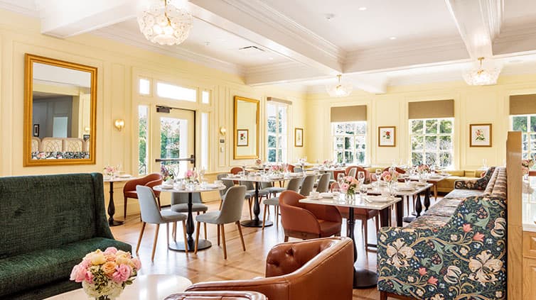 An empty tea room with rose fabric chair and forest green couch.