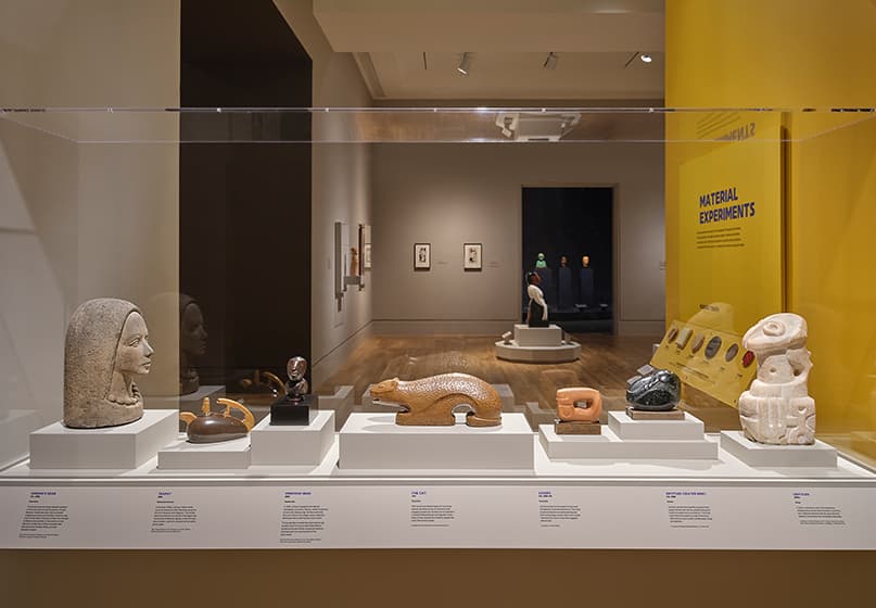 Sculptures on display in a glass case in a gallery.