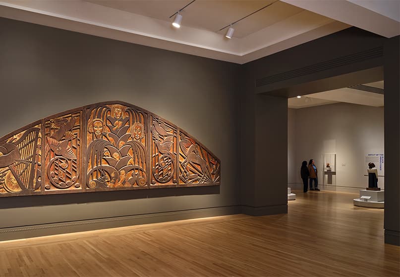 A large carved wood panel on a gallery wall.