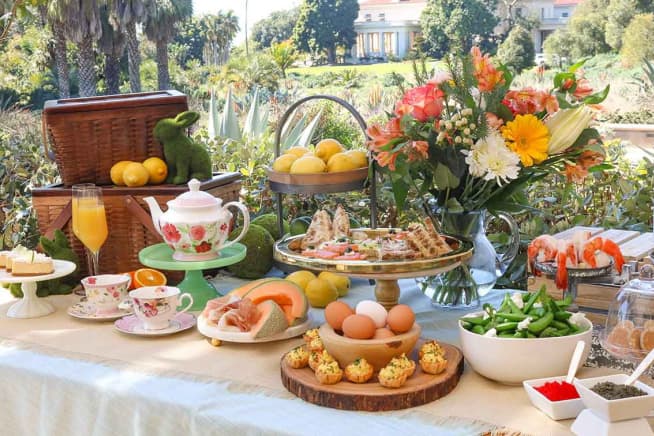 A buffet table outdoors, filled with various dishes, flowers, and spring decor.