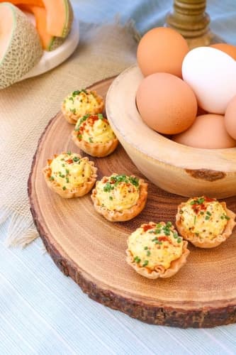 Closeup of a tray with deviled eggs, and eggs in a bowl.