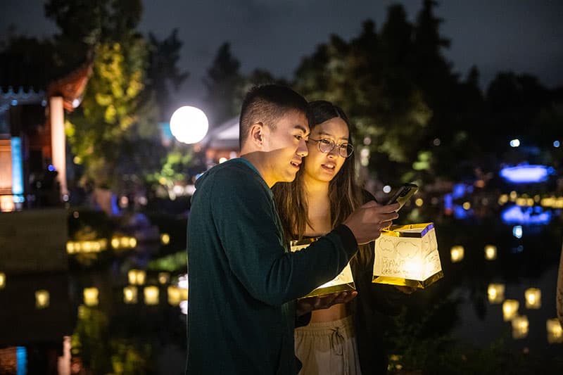 Two people lit at night by a paper lantern.