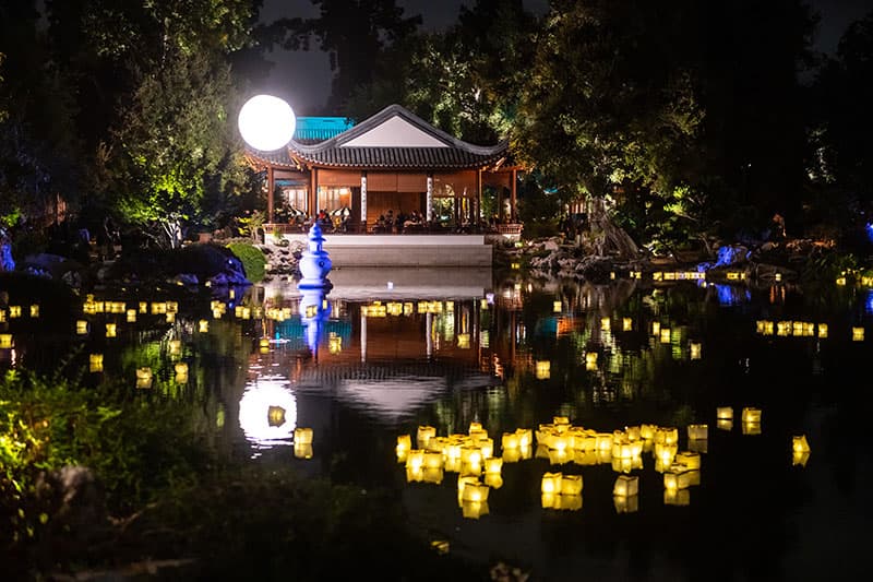 Paper lanterns light up a small lake at night.