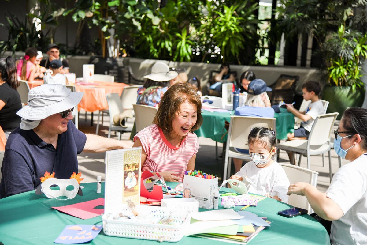 A group of people sit at a table filled with craft supplies.