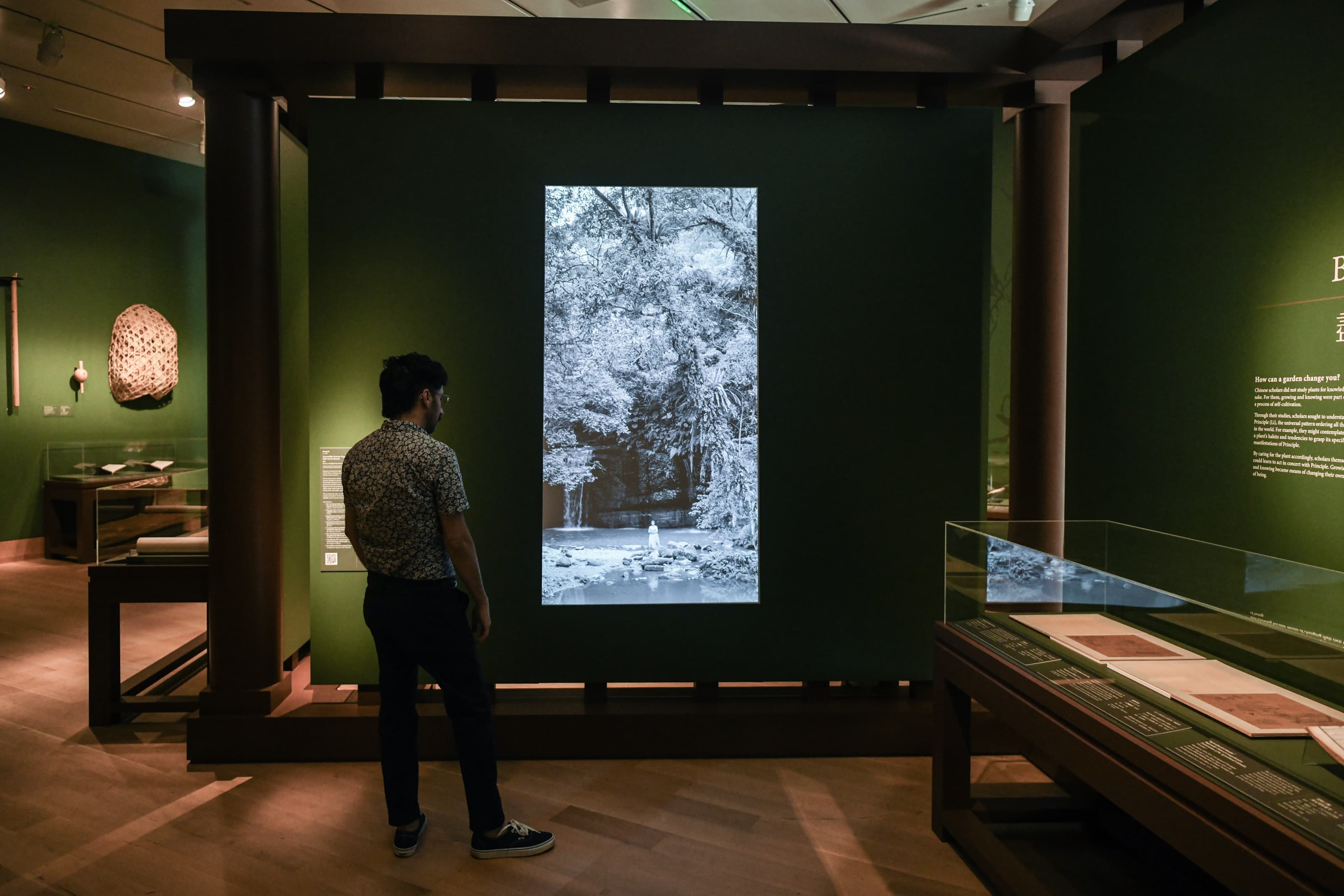 A person watches a black-and-white video projection in a gallery.