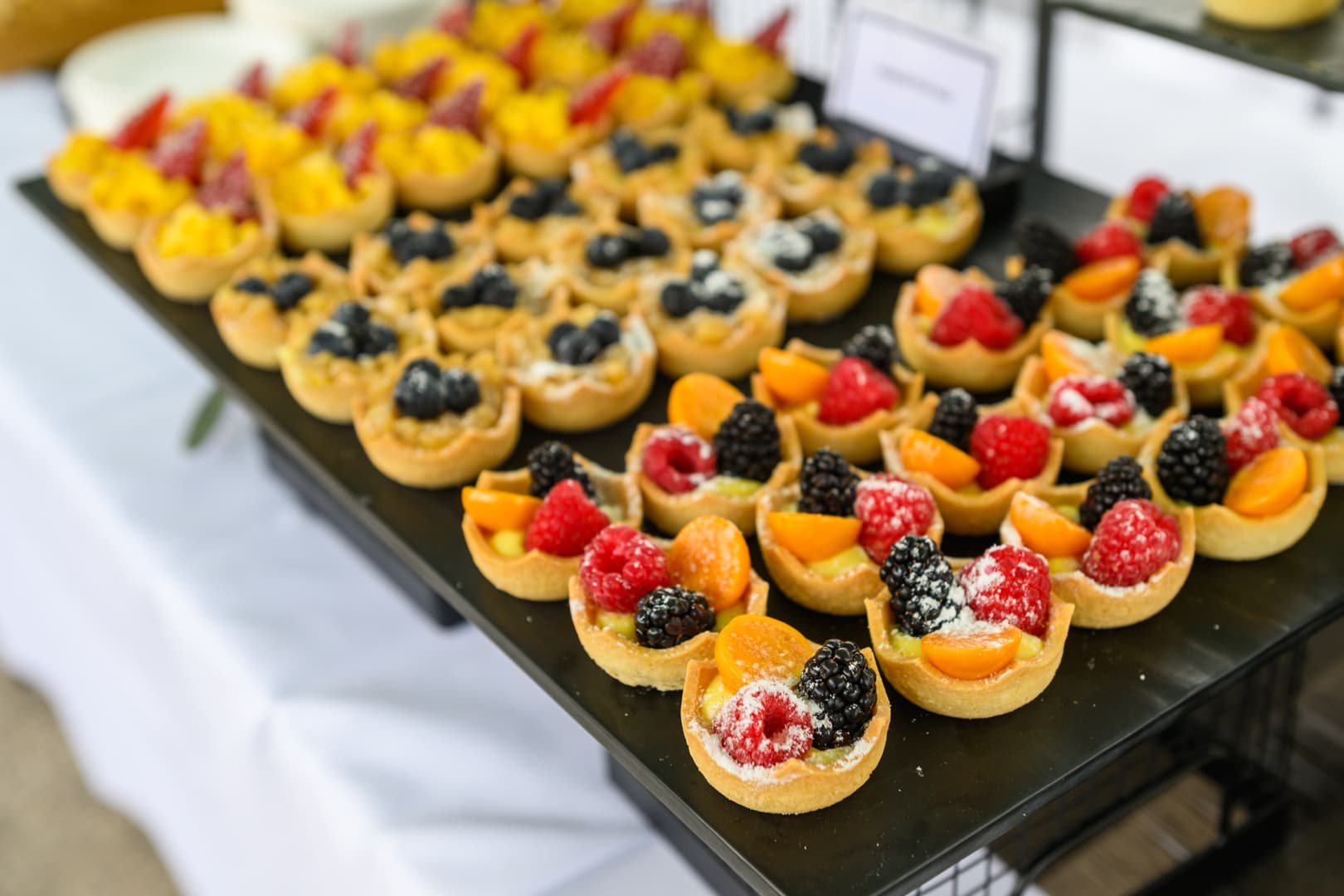 A display of fruit tarts on a white table.