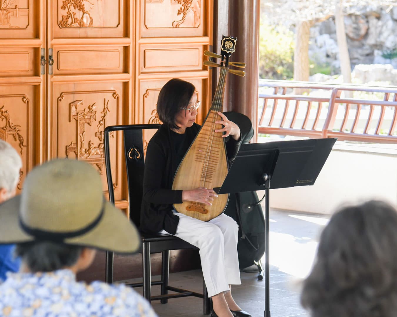 A person plays a plucked string instrument in front of an audience.