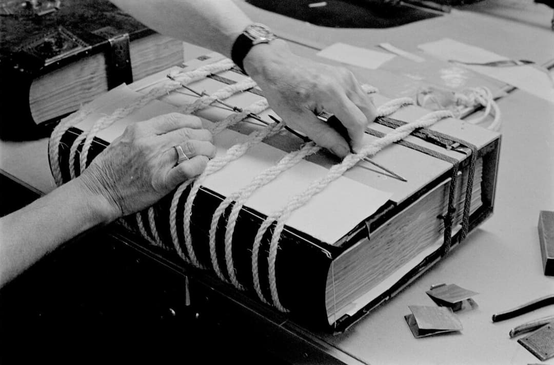 A black and white image of a large book bound with rope.