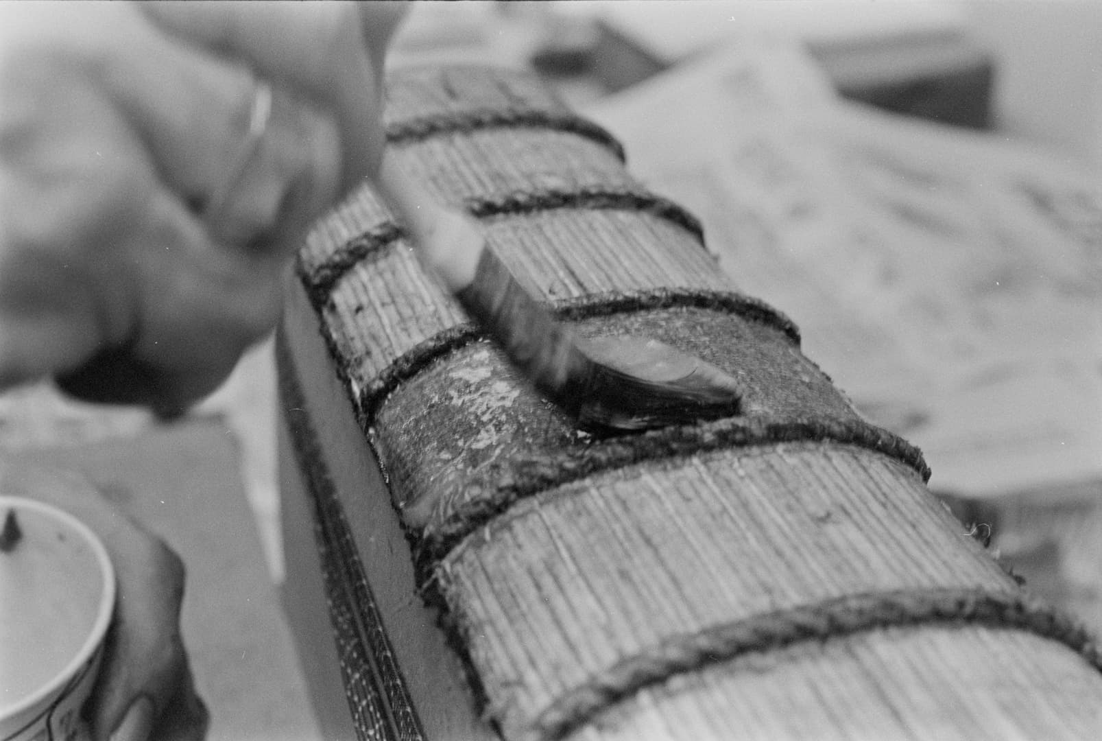 A close-up view of the exposed spine of a book being brushed with glue.