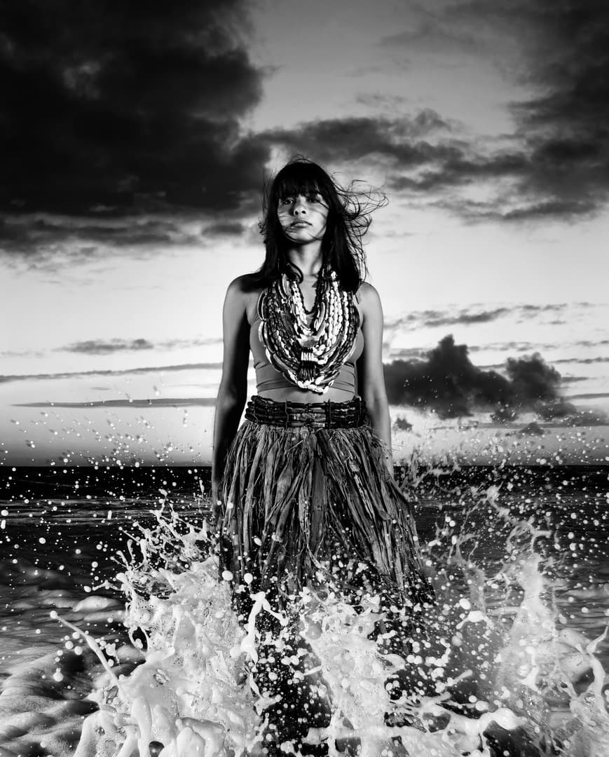 A black-and-white photo of a person standing at the seashore.