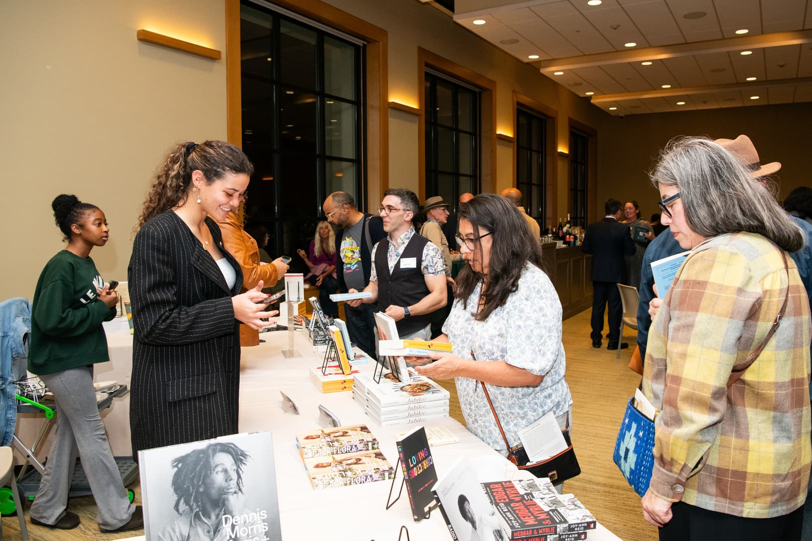 A group of people gather around a table filled with books.