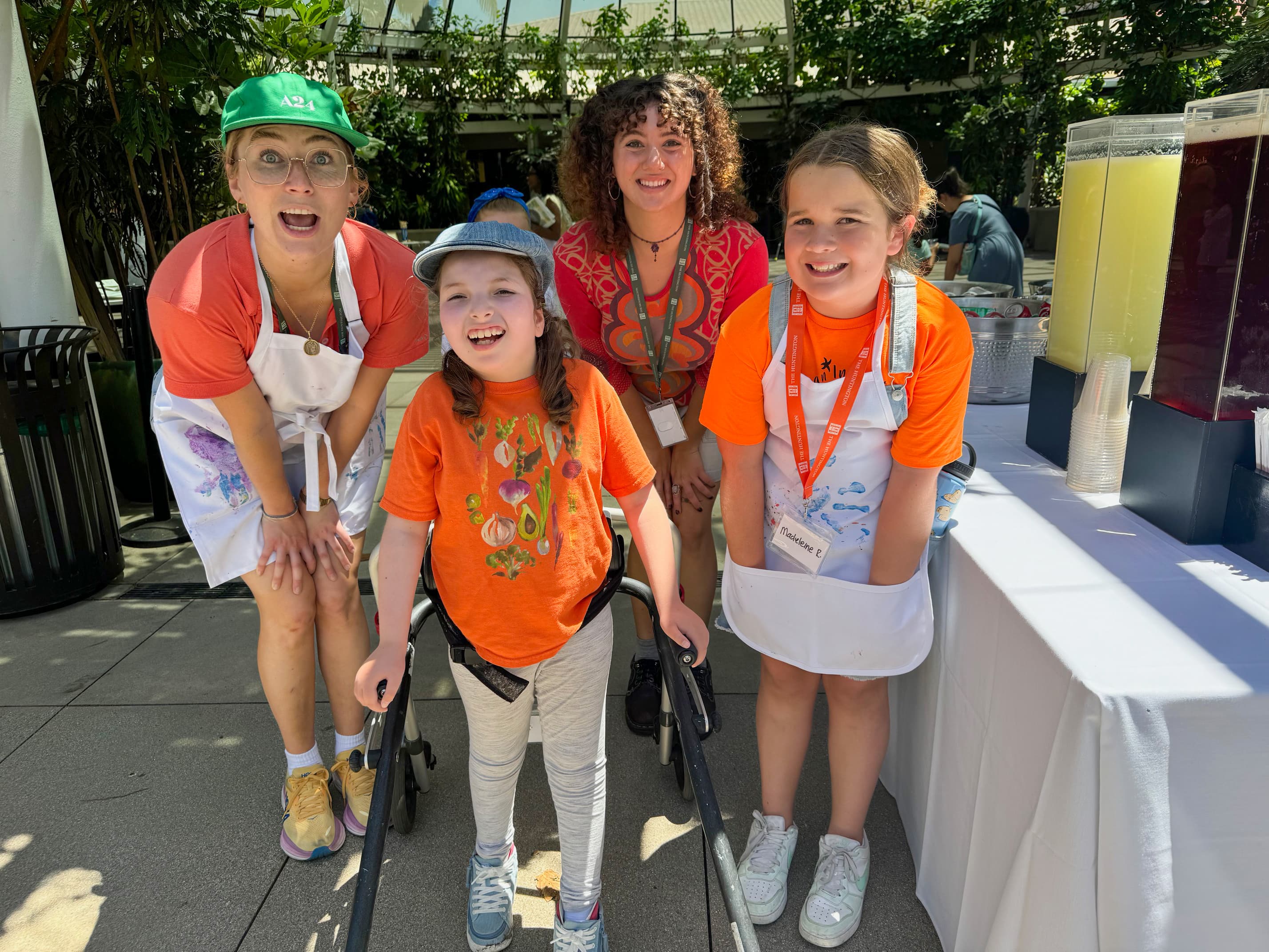 two children, one using a walker, and adults, all wearing orange t-shirts smile exuberantly at the camera