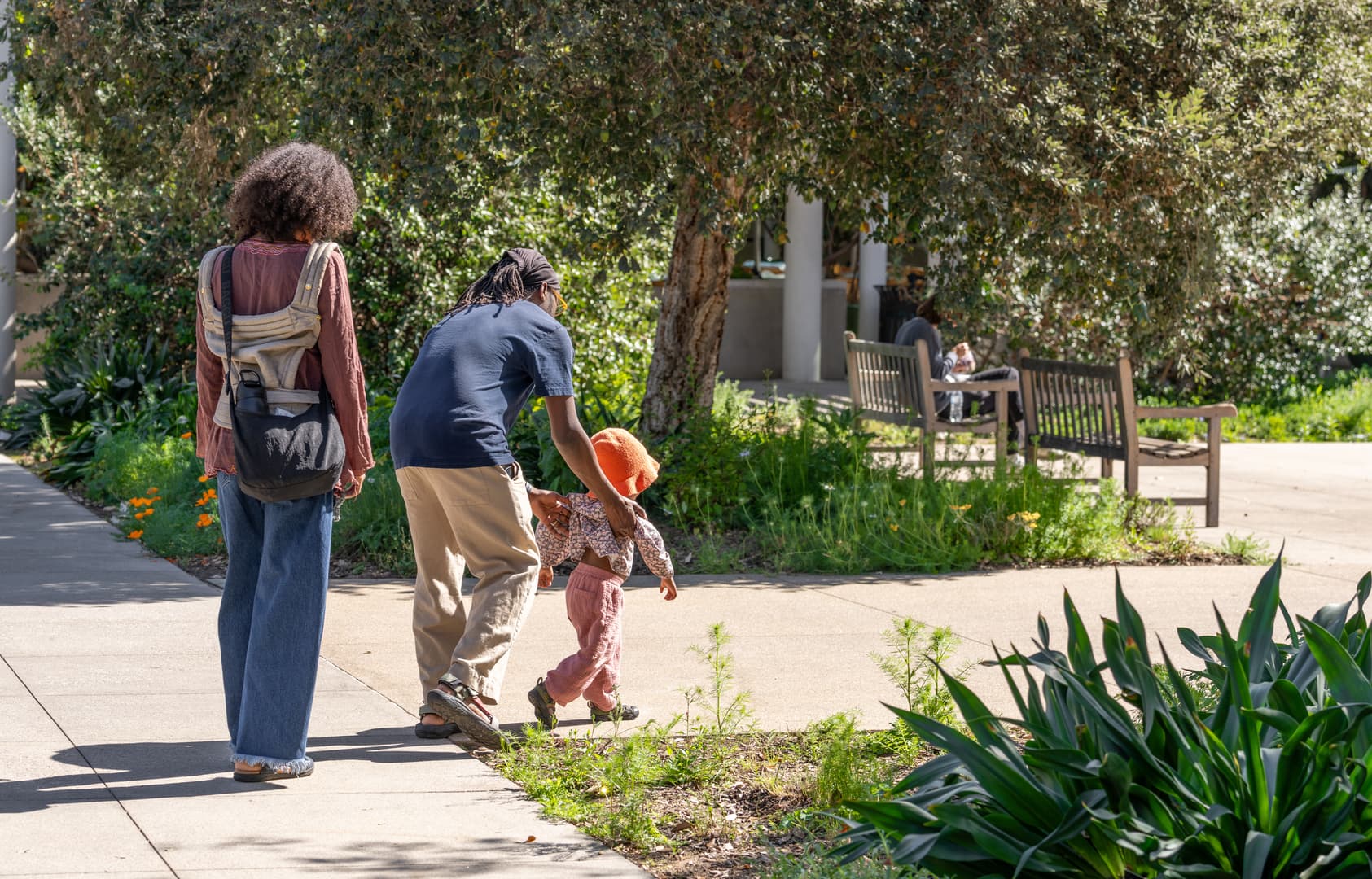 Two adults and a child walk on a pathway.