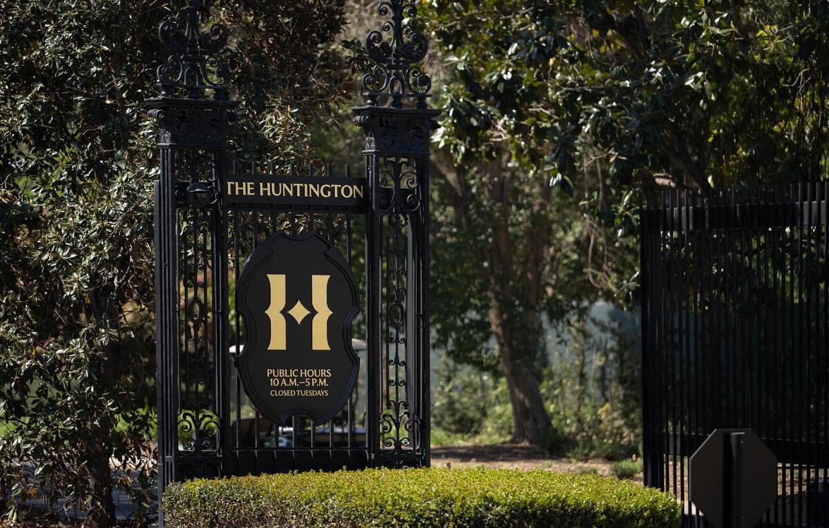 A metal sign that says “The Huntington” surrounded by trees.