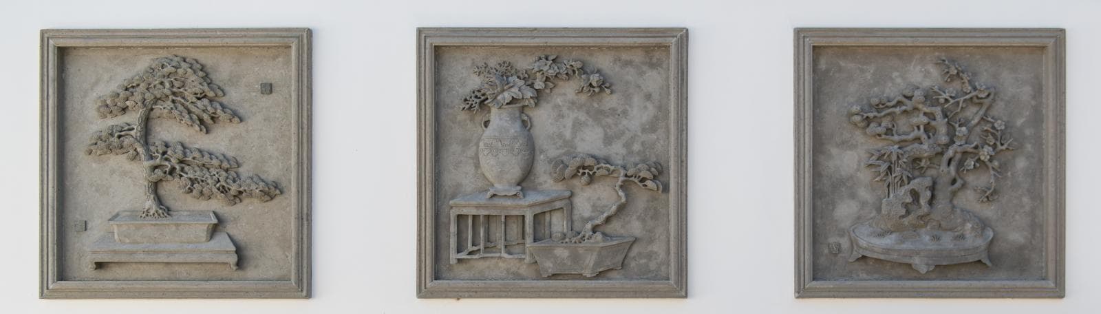 Three square stone artworks.