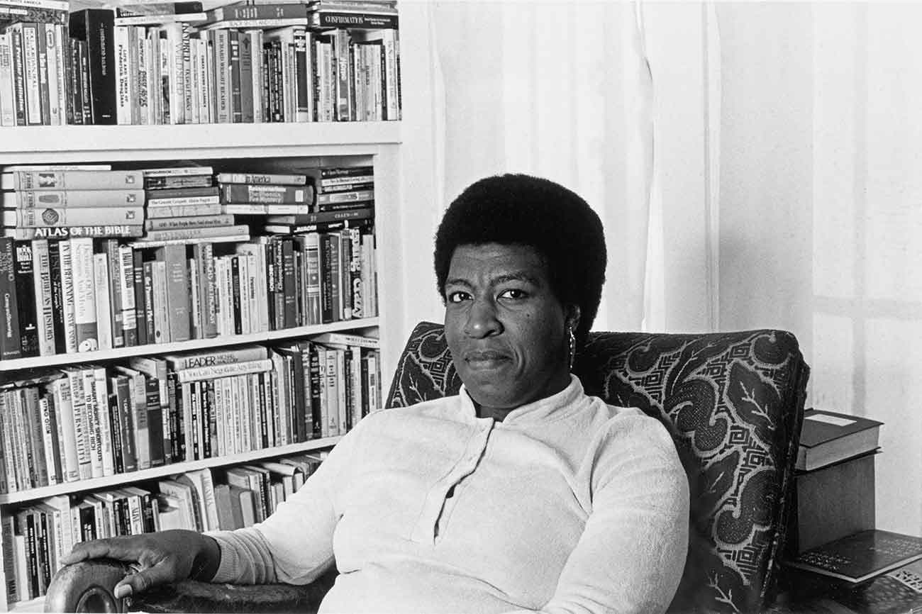 Patti Perret, photograph of Octavia E. Butler seated by her bookcase, 1986. The Huntington Library, Art Collections, and Botanical Gardens. © Patti Perret.
