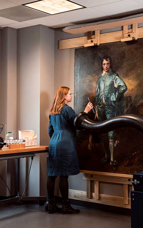 Conservator removing discolored varnish with small swabs