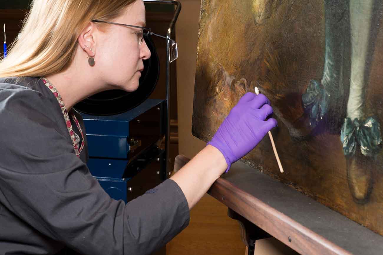 Closeup view of Christina Milton O’Connell, Mary Ann and John Sturgeon Senior Paintings Conservator, removing discolored varnish with small swabs. The Huntington Library, Art Museum, and Botanical Gardens.