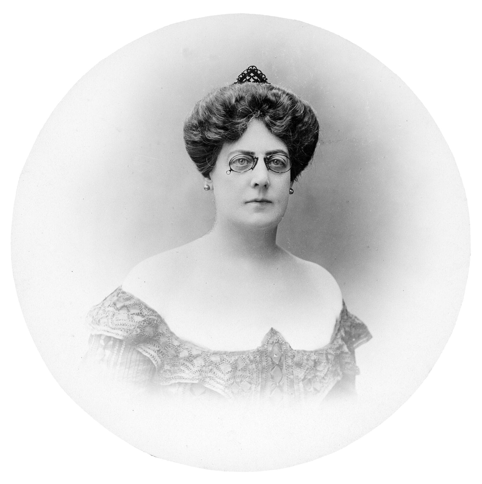 Black-and-white studio portrait of Arabella Huntington by Félix Nadar, Paris, 1903. She is wearing pince-nez glasses, small earrings, and an off-the-shoulder patterned dress, with her hair arranged in an elaborate updo.