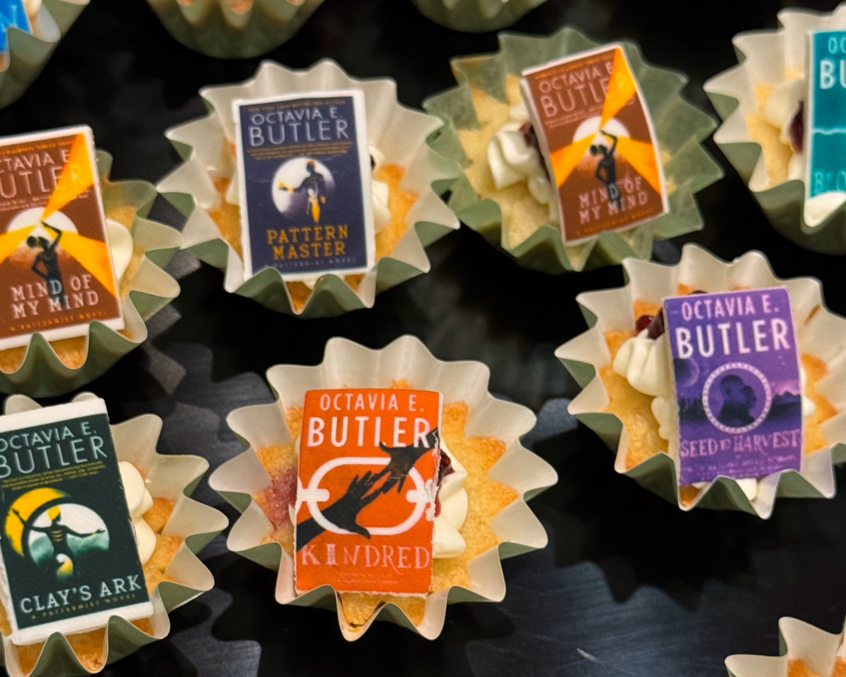 A grid of cupcakes with miniature, edible book-covers as decoration.