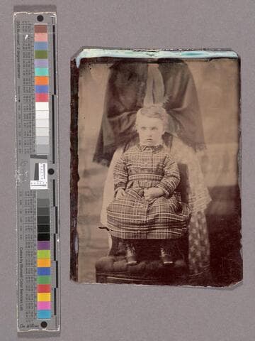 Portrait of young child being held still by a woman