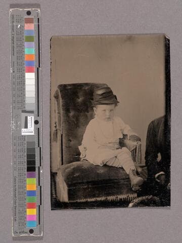 Portrait of young child in a chair and a woman partially out of view