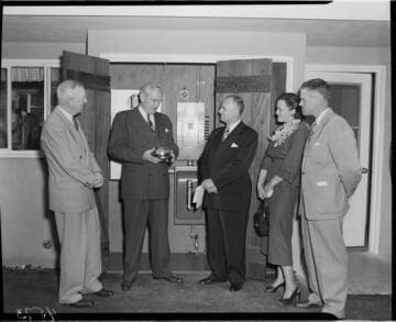 Three Edison men presenting "one millionth" meter to owners in back yard of home