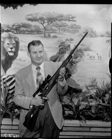 Man holding finished rifle with telescopic sight