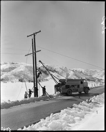 Linemen replacing a pole in the snow