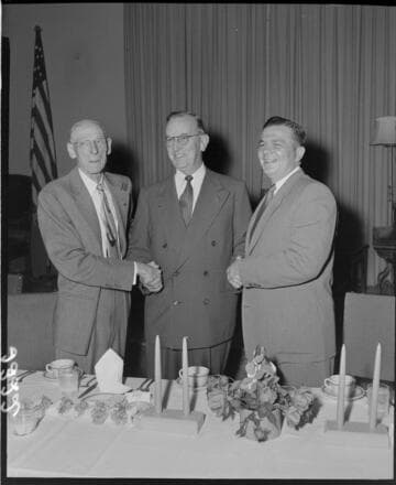 Three men shaking hands at luncheon
