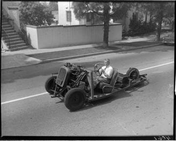 Man driving a 3 wheel vehicle without a body on the street