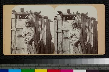 A native woman, most likely Hualapai, stands in front of a wooden shelter