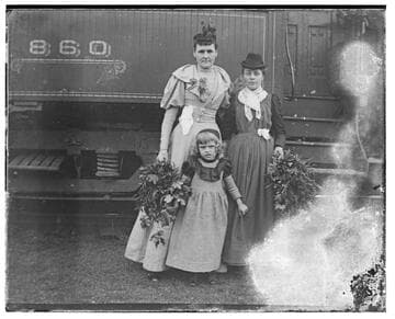 Two women and a girl in front of a train