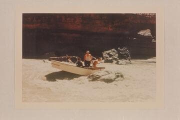 George Wing hung on a rock with one of the Nevills San Juan punts near Johns Canyon.  In the punt are Susie Reilly; Wing; Smith; Pat Reilly.  Mexican Hat gauge:  1190 cfs