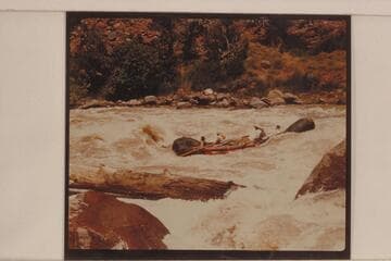 One of the Hatch pontoons carrying two passengers in Hells Half Mile. The passenger in front is A. J. Johnson. The oarsman in front is Brick Johnson. The other oarsman is Dave Rassmussen. The passenger in the stern