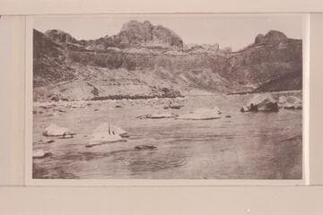 Bert Loper taking empty boat through lower part of No. 1 rapid at mouth of Piute Creek. Chinle, Wingate, Todilto and Navajo from canyon wall. Landslides in Chinle to right and left