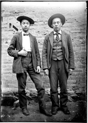 Two Chinese men posing in front of a building, wearing western suits