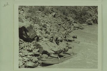 The "Esmeralda" pulled into the rocky shore of the eddy at the right bank at Mile 99.4.  Hudson is unloading equipment preparing to abandon the craft.  Guy Forcier and Edward Hudson watch from the bank.  Bright Angel gauge:  54,000 cfs