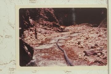 Dangling pipe line in Bright Angel Creek after flood had dug it from wall