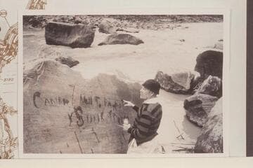 Dock Marston points up the Best Expedition inscription with water.  The lower flat rock at upper center is the one which trapped the Boat No. 1 on July 21, 1891