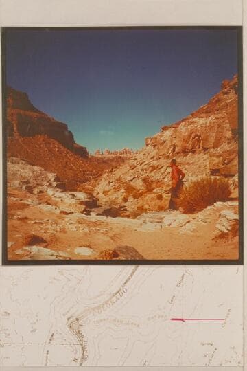 Kent Frost stands at the drop-off of about 30 ft. in the side canyon that enters the Colorado River on the left bank in Cataract Canyon, Mile 213.  Standing Rock country in the background which is the opposite side of the Colorado River