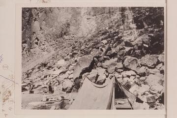 Eddy's boat "Powell" rolled on shore after capsizing when being lined at the head of The Big Drop.  Note food and clothing out to dr.  From the Carey collection
