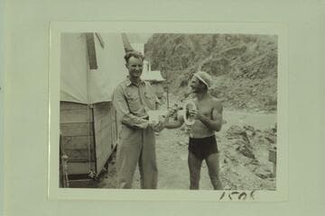 Whipple [head surveyor] of the USBR presents the key to the tent city of Bridge Canyon to Nevills [leader of expedition]