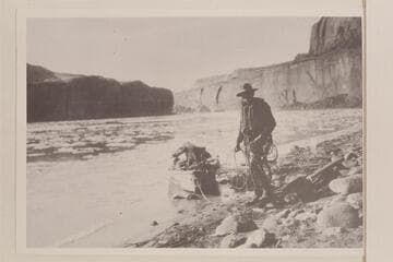 Pat Flattum and the heavily loaded outboard motorboat in Glen Canyon. From album in Wetherill collection